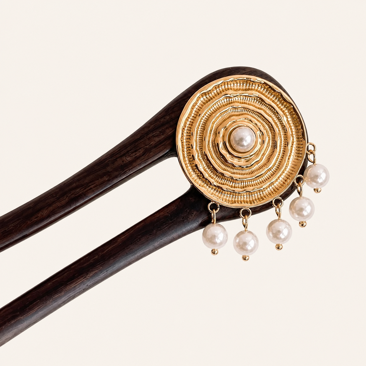 Decorative hair stick with gold circular design and pearl pendants on a white background